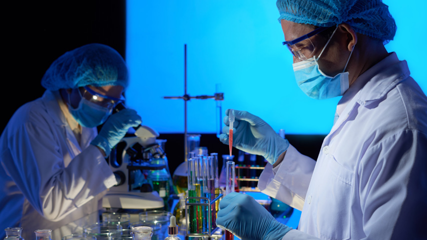 Científicos, con bata, mascarilla, en un laboratorio